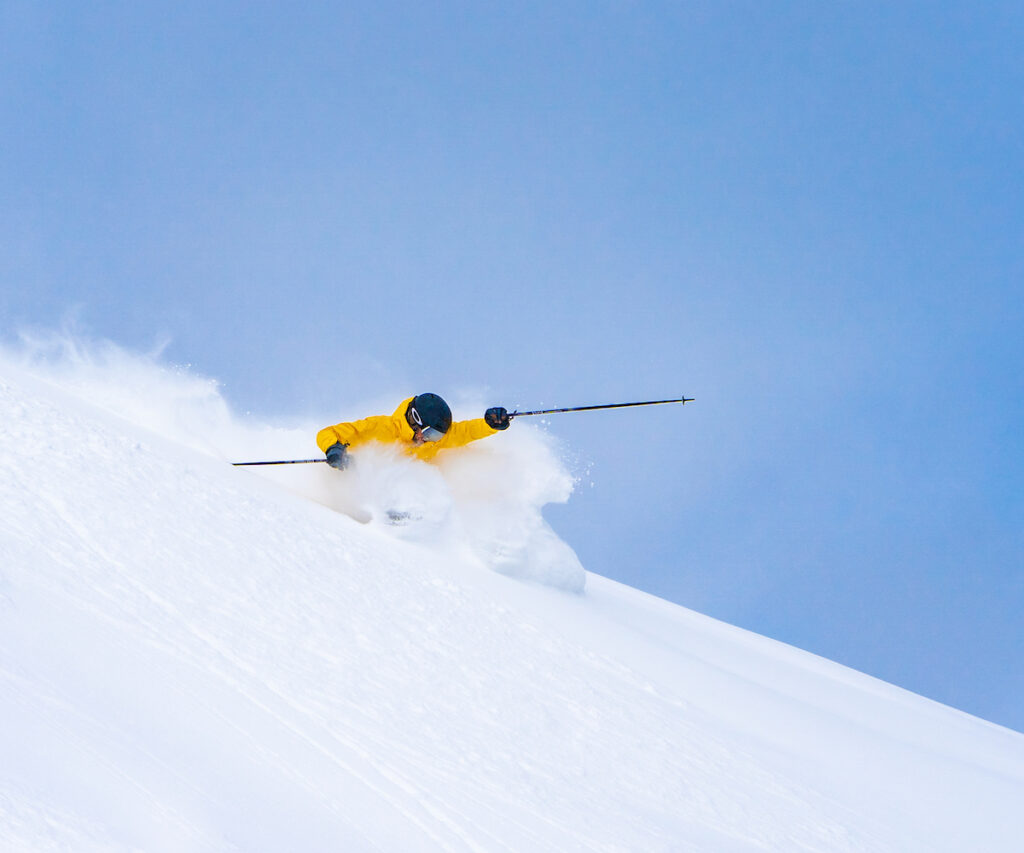 A skier negotiates a steep slope with fresh snow.
